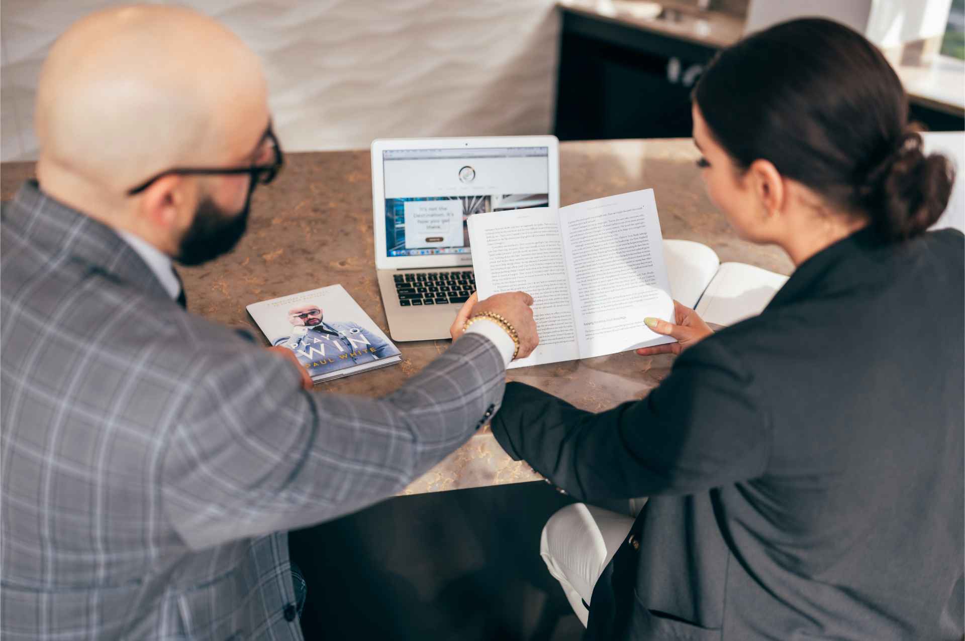 2 professionals meeting together and checking out notes while having laptop open